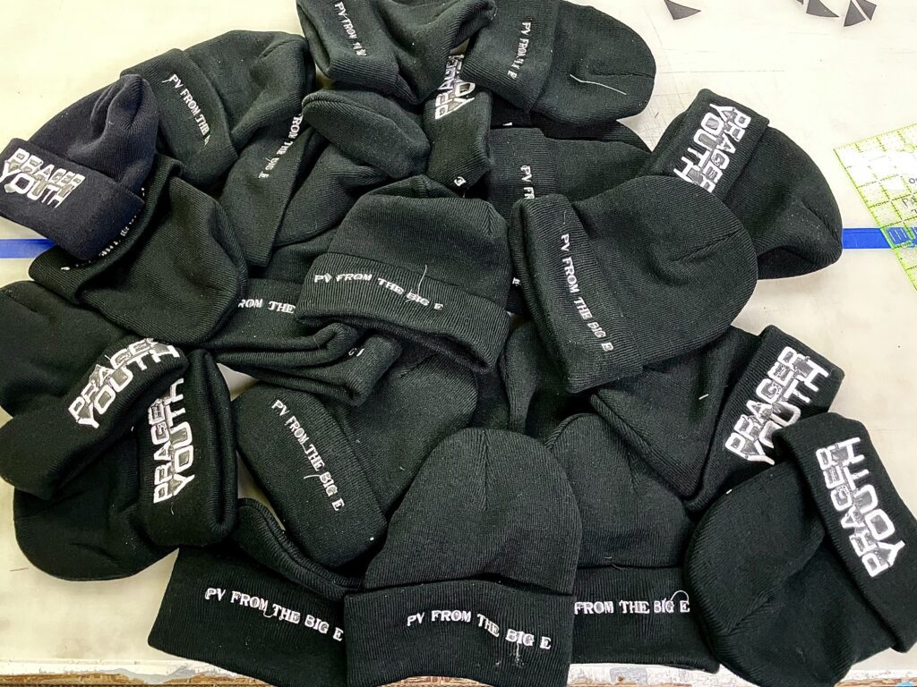 Pile of cuffed embroidered beanies, custom merch for a band in Eugene.